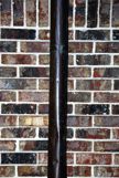 A pole going verical against a brick wall